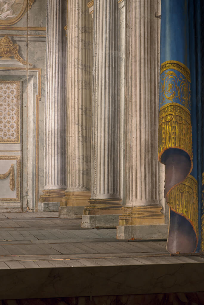Détail du décor de scène du Temple de Minerve : « … colonnes cannelées, ton de marbre blanc, ornements rehaussés d’or » vus du côté cour. © Château de Versailles / Thomas Garnier.
